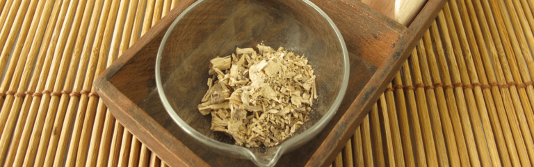 Wood chips rest inside a glass bowl, placed on a wooden tray, atop a bamboo mat.