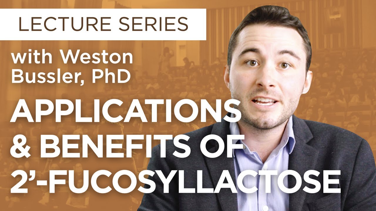 A person jogs across rocky terrain wearing an orange shirt and black leggings, set against a backdrop of lush green hills and snow-capped mountains.