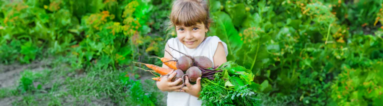 girl in garden with beets and carrots